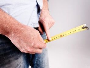 a man measures the length of his penis before lifting with soda